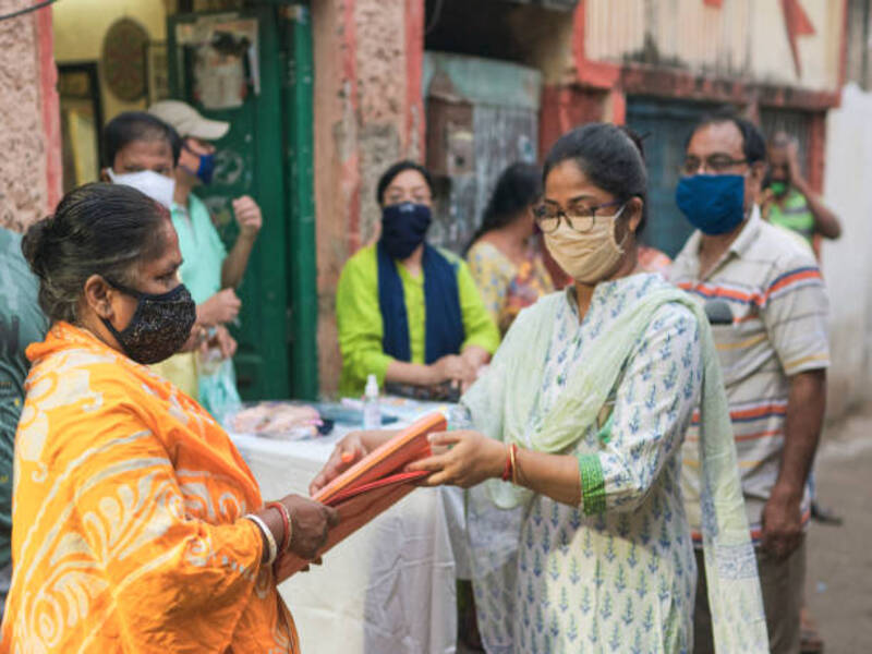 Hazra, Kolkata, 10/18/2020: Members of Kolkata Municipal Corporation (KMC) and local welfare association donating new clothes to poor and needy people of a locality, just few days before commencement of Durga puja, the biggest festival in West Bengal, as well as in Eastern India. Everyone is seen wearing face mask for protection from coronavirus infection.